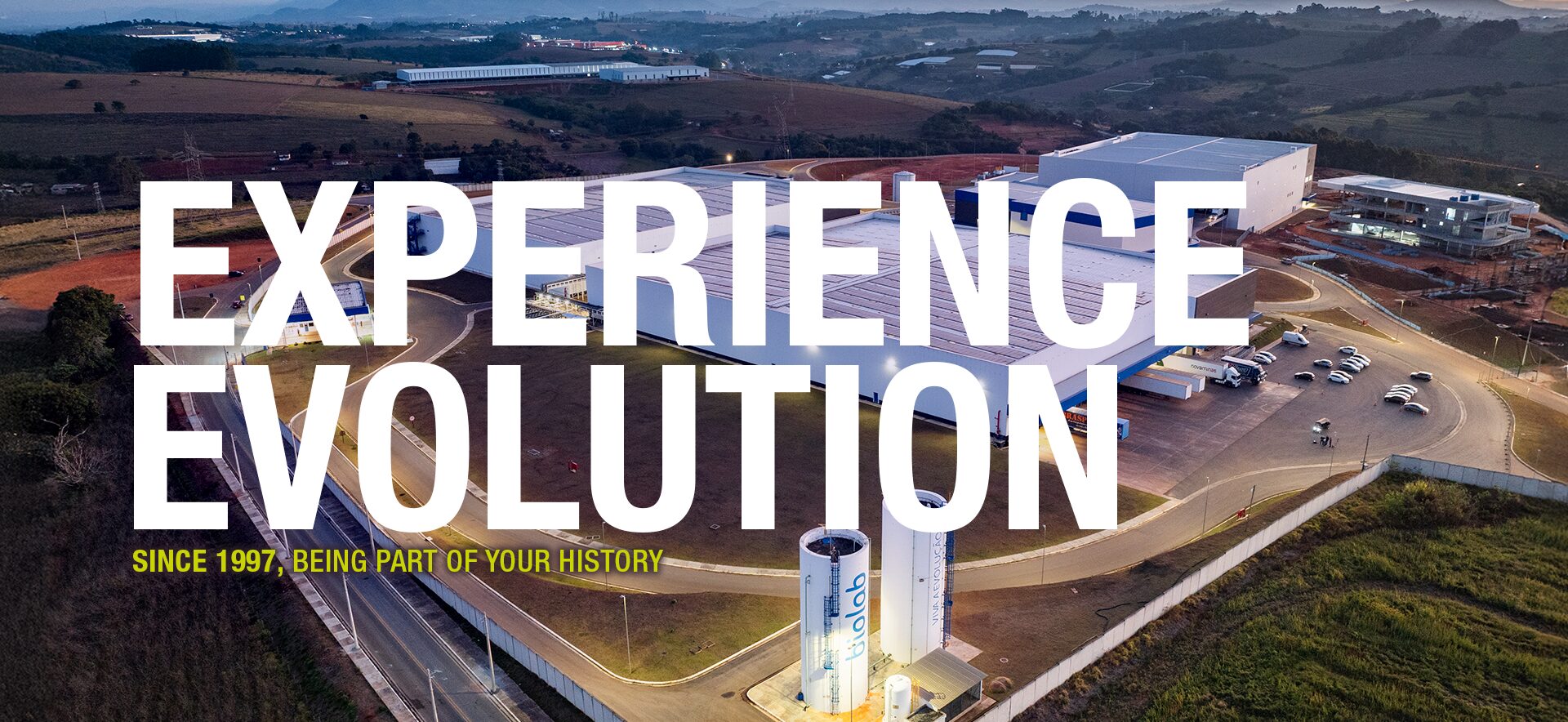 Banner with an aerial photo of the Biolab plant in Pouso Alegre and the text Viva a Evolução above it